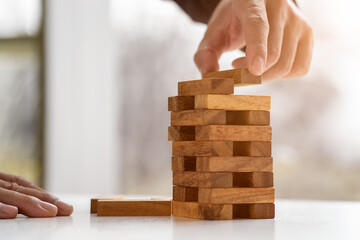 Close up hand of Business has piling up and stacking a wooden block.Businessman Building The Success,plan and strategy in business,risk concept.