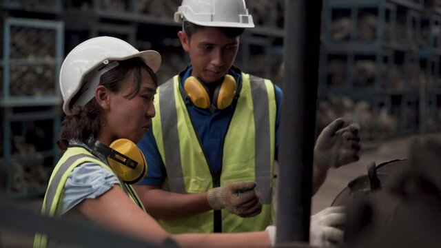 group of warehouse worker  checking list inventory of old used car engine in garage store.  woman manager and supervisor man in Recycle motor factory auto parts