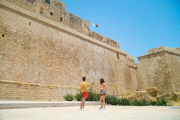 Couple standing near the wall of Castello citadel of Victoria in Gozo, Malta