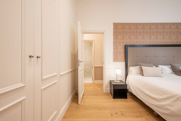 Fototapeta na wymiar Bedroom with king size bed, white lacquered carpentry cabinets and chestnut flooring in a vacation rental apartment.