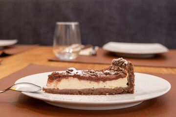 Portion of delicious cheesecake with some chocolate and icing sugar on the restaurant table