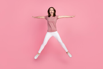 Full size photo of funny brunette young lady jump wear t-shirt jeans isolated on pink color background