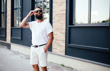 Street portrait of a young bearded hipster guy wearing a white blank t-shirt. Mock-up for print. T-shirt template.