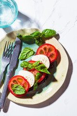 Caprese sandwich on white marble background. Toast with mozzarella, tomato and basil.