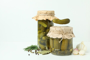 Jars of pickles and ingredients on white background