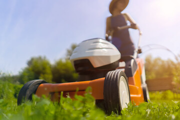 A woman gardener is trimming grass with the grass cutter, bottom view