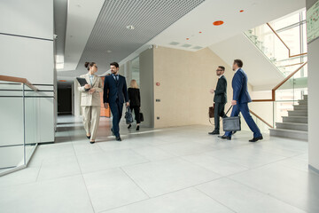 Group of business people walking through the office corridor durig working day