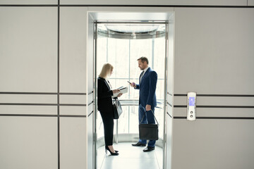 Two business people standing in elevator of modern office building