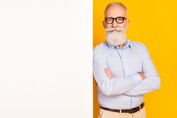 Photo of attractive sweet age gentleman wear blue shirt glasses arms crossed white empty space isolated yellow color background