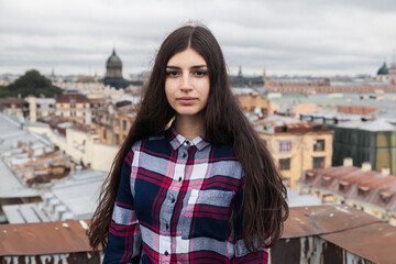 portrait of an Armenian girl with fluttering long black hair in a checkered shirt and jeans on a...