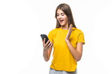 Portrait of a surprised attractive girl holding mobile phone and looking at camera over white background