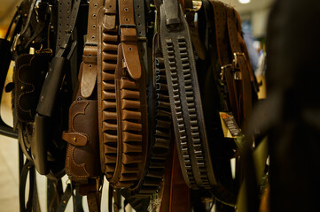 Different leather bandoliers in gun store, nobody