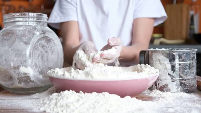 Children's hands are covered in flour. The child cooks.
