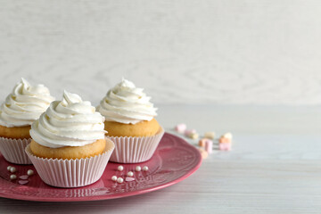 Delicious cupcakes with cream on white wooden table. Space for text