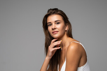 Naklejka premium Beautiful smiling girl with clean skin, natural make-up, and white teeth on grey background