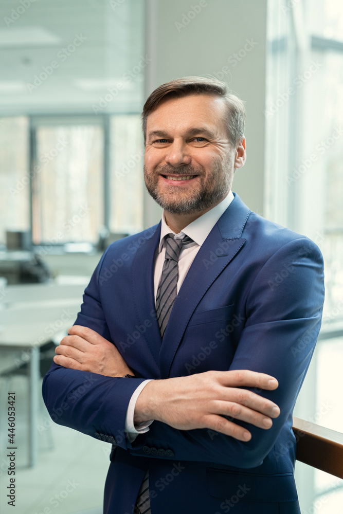 Canvas Prints Portrait of successful mature businessman in elegant suit smiling at camera while standing at office