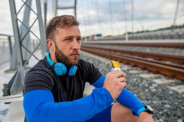 An athlete with a beard eats a bar of chocolate after training