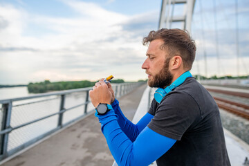 An athlete with a beard eats a bar of chocolate after training