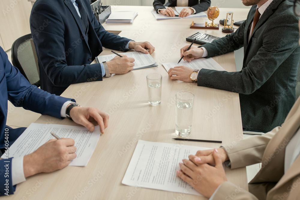 Aufkleber close-up of business people sitting at the table and making notes in documents during a business mee