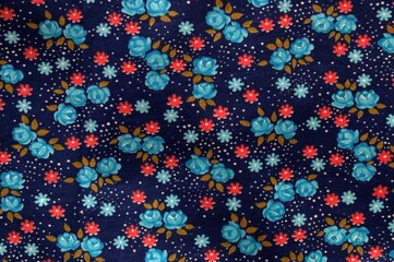 The texture of the fabric with painted flowers. Blue background, red and blue flowers