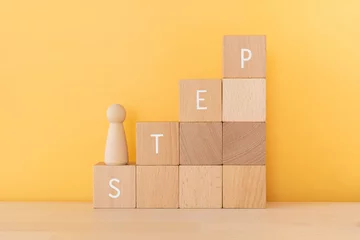 Fotobehang ステップ｜「STEP」と書かれた積み木と人形 © ELUTAS