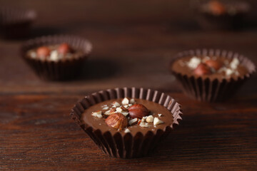 Delicious chocolate candies with hazelnuts on wooden table, closeup