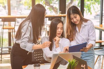 Group of asian young business woman working and communicating while sitting at the office desk together with charts and graphs banner, double exposure successful teamwork,business planning concept.