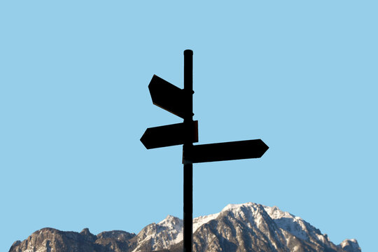 Mountains with black hiking trailhead post showing directions with copy space and blue sky solid background. Concept of travel, hiking and mountaineering.