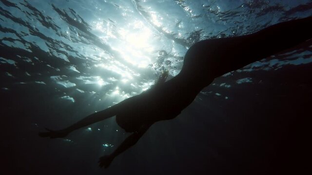 Silhouette di una sirena che nuota nell'oceano