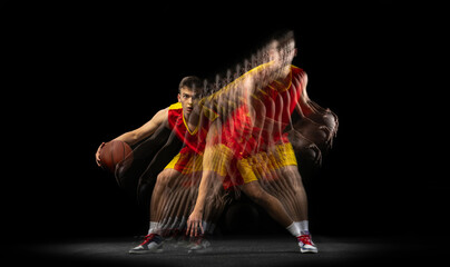 Professional basketball player playing basketball isolated on dark background with stroboscope...