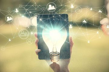 Double exposure of light bulb hologram and woman holding and using a mobile device. Idea concept.