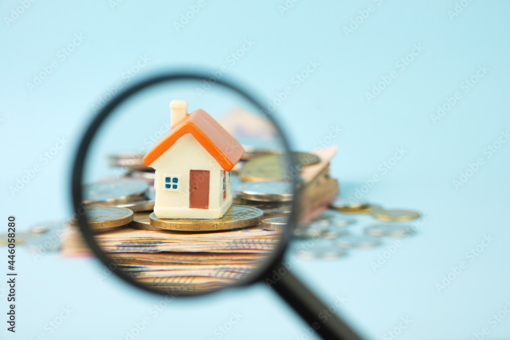 Wall mural miniature house and money under a magnifying glass. concept of real estate investment, mortgage, hom