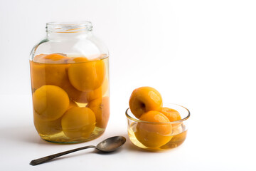 Peaches canned in a glass bowl and in a jar on a white background