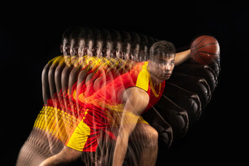 One young basketball player training with ball isolated on dark background with stroboscope effect....