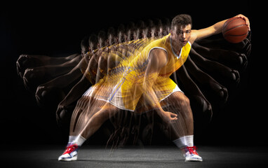 Young caucasian basketball player in motion and action isolated on dark background with stroboscope...