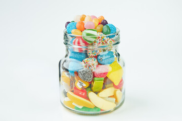 Assorted candies in a glass jar on a white background.
