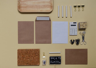 Fototapeta na wymiar Back to school creative concept. Pattern of scissors, calculator, envelopes, notebook, chalk and other stationery in a chaotic manner lying on beige paper background. Flat lay.