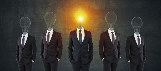 Light bulb headed businessmen in suits on chalkboard background. Teamwork, idea and leadership...