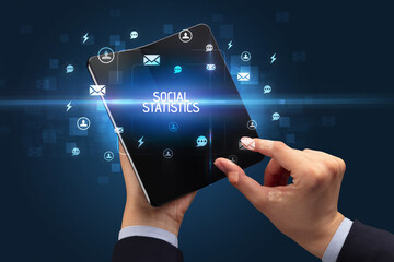 Obraz premium Businessman holding a foldable smartphone, social media concept