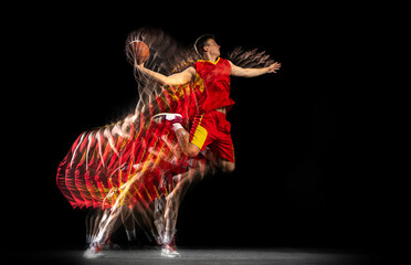 Flight. Young caucasian basketball player in motion and action isolated on dark background with...
