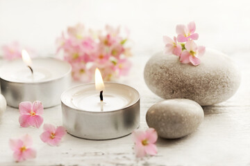 Fototapeta na wymiar SPA still life with aromatherapy candle and little pink flowers