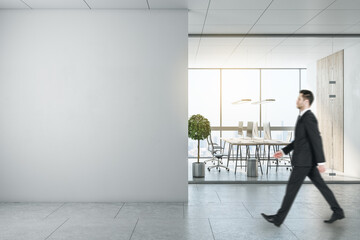 Businessman walking in modern coworking office interior with empty mockup place, city view, equipment and furniture, law and legal concept. Mock up.