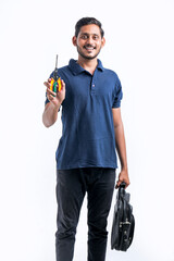 Young indian electrician holding tools in hand and standing over white background.