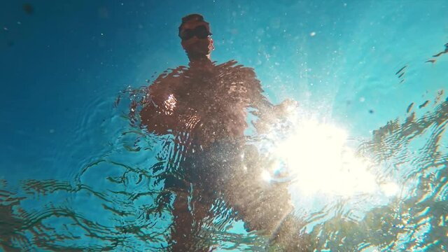 Man in swimglasses gesting, visible from under the water of the Aegean sea, Greece