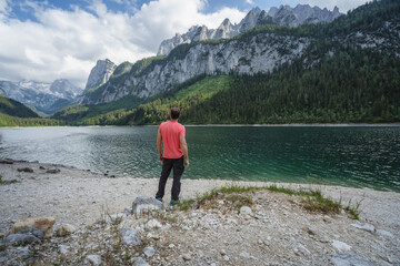 Man enjoying Dachstein Mountains reflected in Gosau lake, Austria