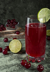 Fresh cool cherry compote with lime in a glass glass on the table.