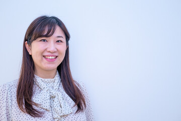 Fototapeta premium 白背景の前でカメラに向かってほほ笑む女性