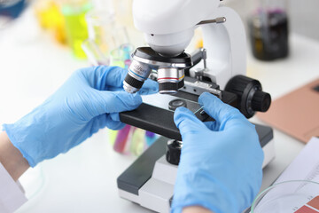 Scientist in gloves holds glass from microscope