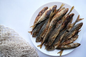 Fried horse mackerel and barbecue on a plate against a light concrete background. Top view of the table. Healthy food concept, Mediterranean diet. Cope with space