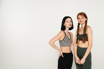 Sportswomen with freckles and vitiligo looking at camera isolated on grey